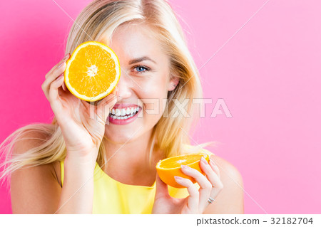 Happy young woman holding orange halves Happy young woman holding orange halves 32182704