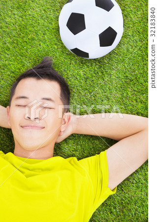 young man lying on a meadow with a football young man lying on a meadow with a football 32183840