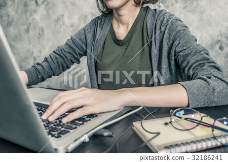 Casual young woman using a laptop on the desk. Casual young woman using a laptop on the desk. 32186241