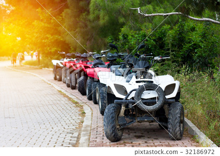 Some quad bikes standing near road Some quad bikes standing near road 32186972