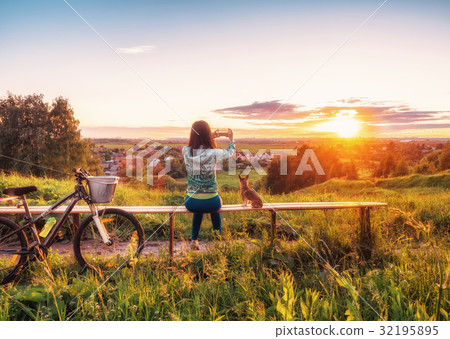 Young girl  taking pictures of a beautiful sunset 32195895