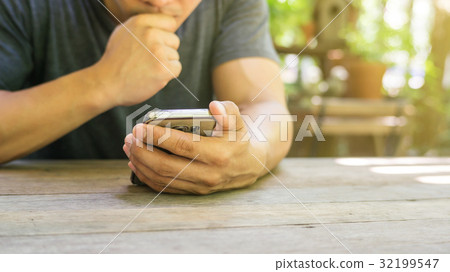 Man using a smartphone in a garden. 32199547