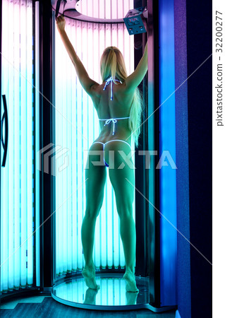 Rear view of slender blonde tans in tanning booth Rear view of slender blonde tans in tanning booth 32200277