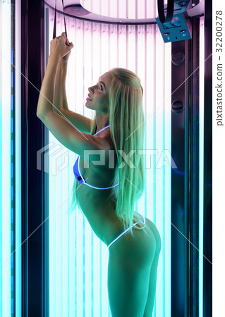 Tanning procedure. Slender woman tans in solarium Tanning procedure. Slender woman tans in solarium 32200278