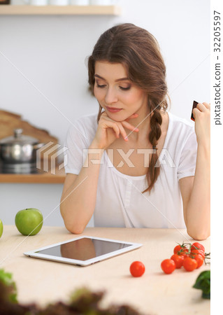 Young woman looking for a new recipe for cooki Young woman looking for a new recipe for cooki 32205597