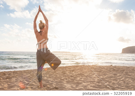 Woman practicing yoga on sea beach at sunset. 32205919
