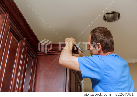 Carpenter brad using nail gun to Crown Moulding  32207391