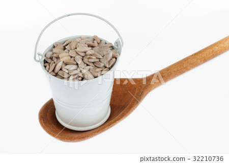Full bucket of sunflower seeds stands in  spoon. 32210736