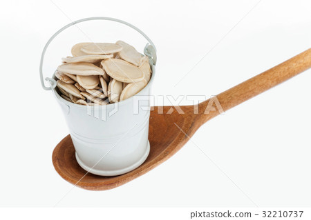 Full bucket of pumpkin seeds stands in spoon. Full bucket of pumpkin seeds stands in spoon. 32210737