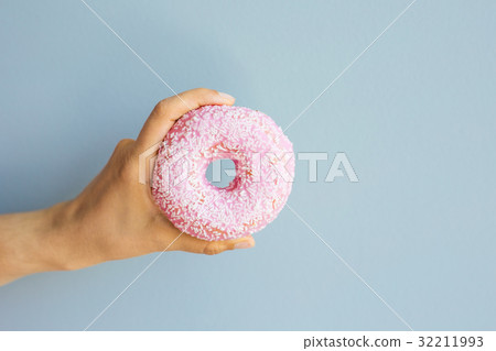 Woman holding pink delicious donut on blue Woman holding pink delicious donut on blue 32211993