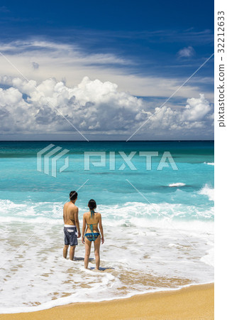 Vacation couple walking on beach together Vacation couple walking on beach together 32212633