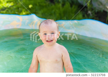 Baby swims in a plastic pool in the nature 32213708