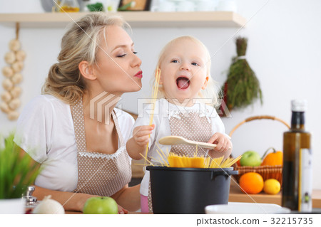 Mother kiss her child daughter while cooking pasta Mother kiss her child daughter while cooking pasta 32215735