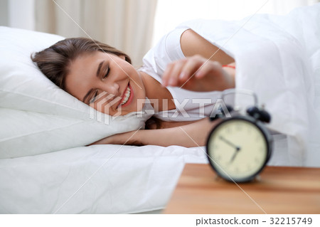 Sleepy young brunette woman stretching hand to 32215749