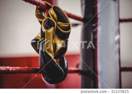 Yellow boxing gloves hanging off the boxing ring Yellow boxing gloves hanging off the boxing ring 32225625