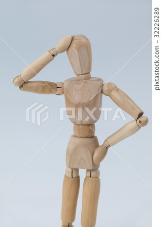 Confused wooden figurine standing with hand on head 32226289