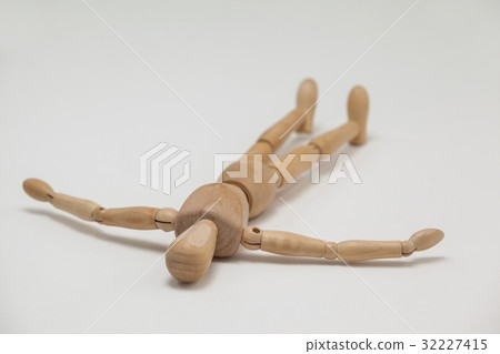 Wooden figurine lying on floor with arms spread 32227415