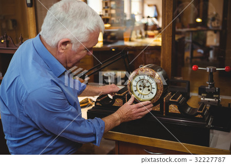 Horologist checking a clock in workshop Horologist checking a clock in workshop 32227787