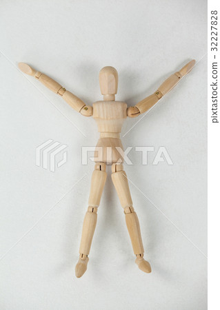 Wooden figurine lying on floor with arms spread wide 32227828