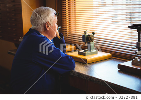 Thoughtful horologist looking through window Thoughtful horologist looking through window 32227881