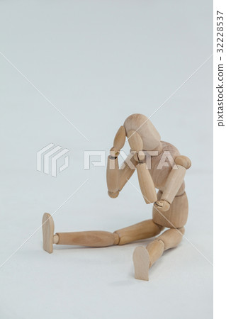 Tensed wooden figurine sitting with hands on head 32228537