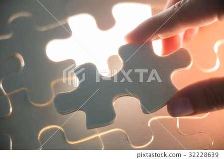 Woman placing missing piece in jigsaw puzzle 32228639