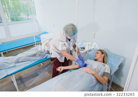 Professional nurse making an injection to a woman Professional nurse making an injection to a woman 32233265