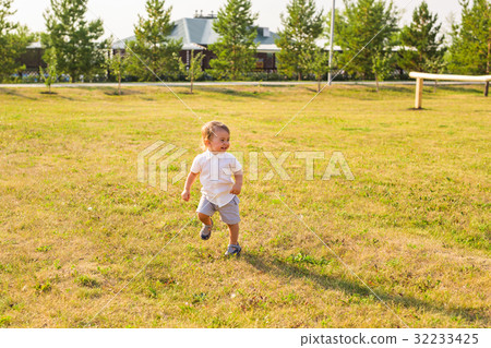 Happy baby boy running on summer field Happy baby boy running on summer field 32233425