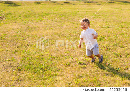 Happy baby boy running on summer field Happy baby boy running on summer field 32233426