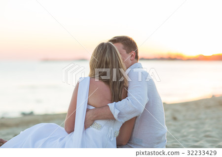 Young love couple sitting together on beach Young love couple sitting together on beach 32233429