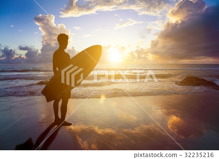 surfer man standing on beach  holding  surfboard 32235216