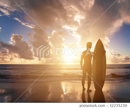 surfer man standing on beach watching the sunrise surfer man standing on beach watching the sunrise 32235239