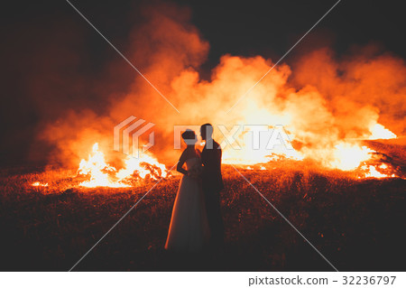 Amazing wedding couple near the fire at night Amazing wedding couple near the fire at night 32236797