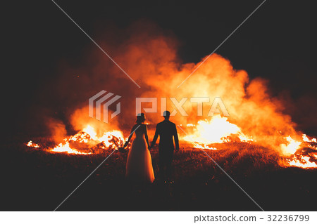 Amazing wedding couple near the fire at night Amazing wedding couple near the fire at night 32236799