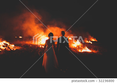 Amazing wedding couple near the fire at night Amazing wedding couple near the fire at night 32236800
