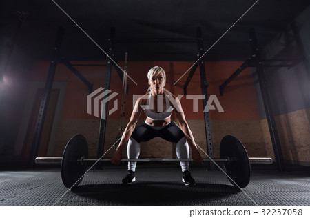 Muscular young fitness woman lifting a weight in 32237058