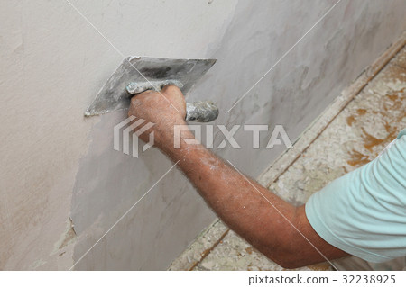 Worker spreading plaster to damaged wall 32238925