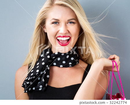 Happy young woman holding a shopping bag Happy young woman holding a shopping bag 32242774