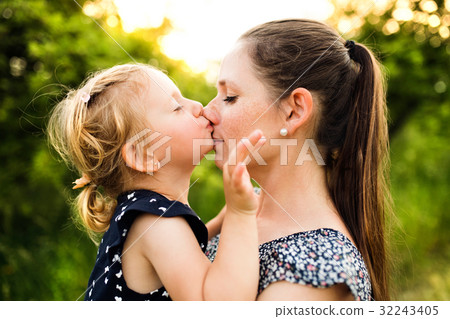 Young mother in nature holding little daughter in 32243405