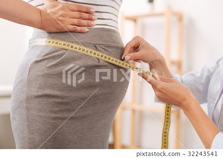 Nice woman measuring belly of her client Nice woman measuring belly of her client 32243541