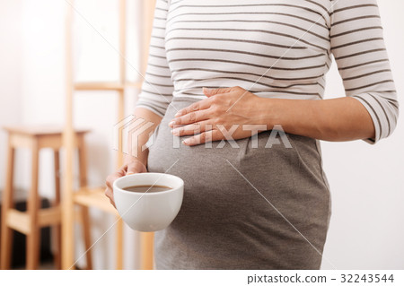 Plerasant pregnant woman holding a cup of coffee Plerasant pregnant woman holding a cup of coffee 32243544
