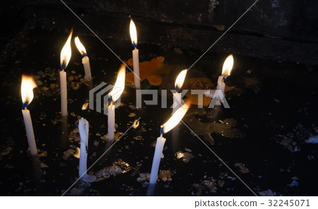 Lit white candles with melted wax on dark water. 32245071