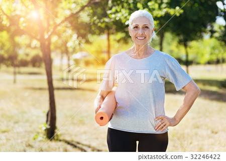 Positive senior woman holding yoga carpet Positive senior woman holding yoga carpet 32246422