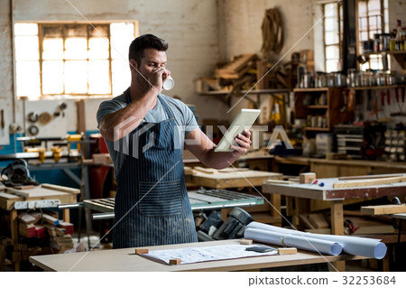 carpenter using his tablet and drinking a coffee 32253684