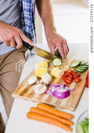 Mid-section of man chopping vegetable in kitchen 32254119