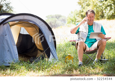 senior man is reading and talking on the phone senior man is reading and talking on the phone 32254544