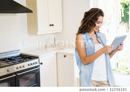 Young woman using digital tablet in kitchen Young woman using digital tablet in kitchen 32256191