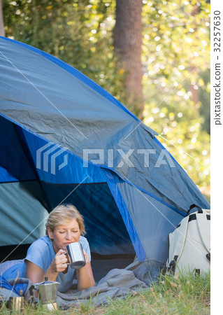 Mature woman laying and drinking on a mug Mature woman laying and drinking on a mug 32257630