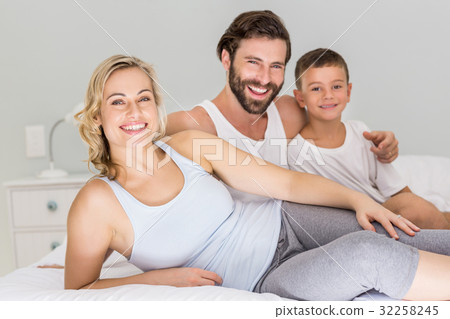 Portrait of parents and son sitting on bed in bedroom 32258245