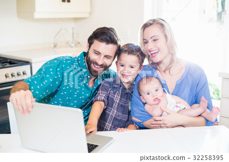 Parents and kids using laptop in living room Parents and kids using laptop in living room 32258395